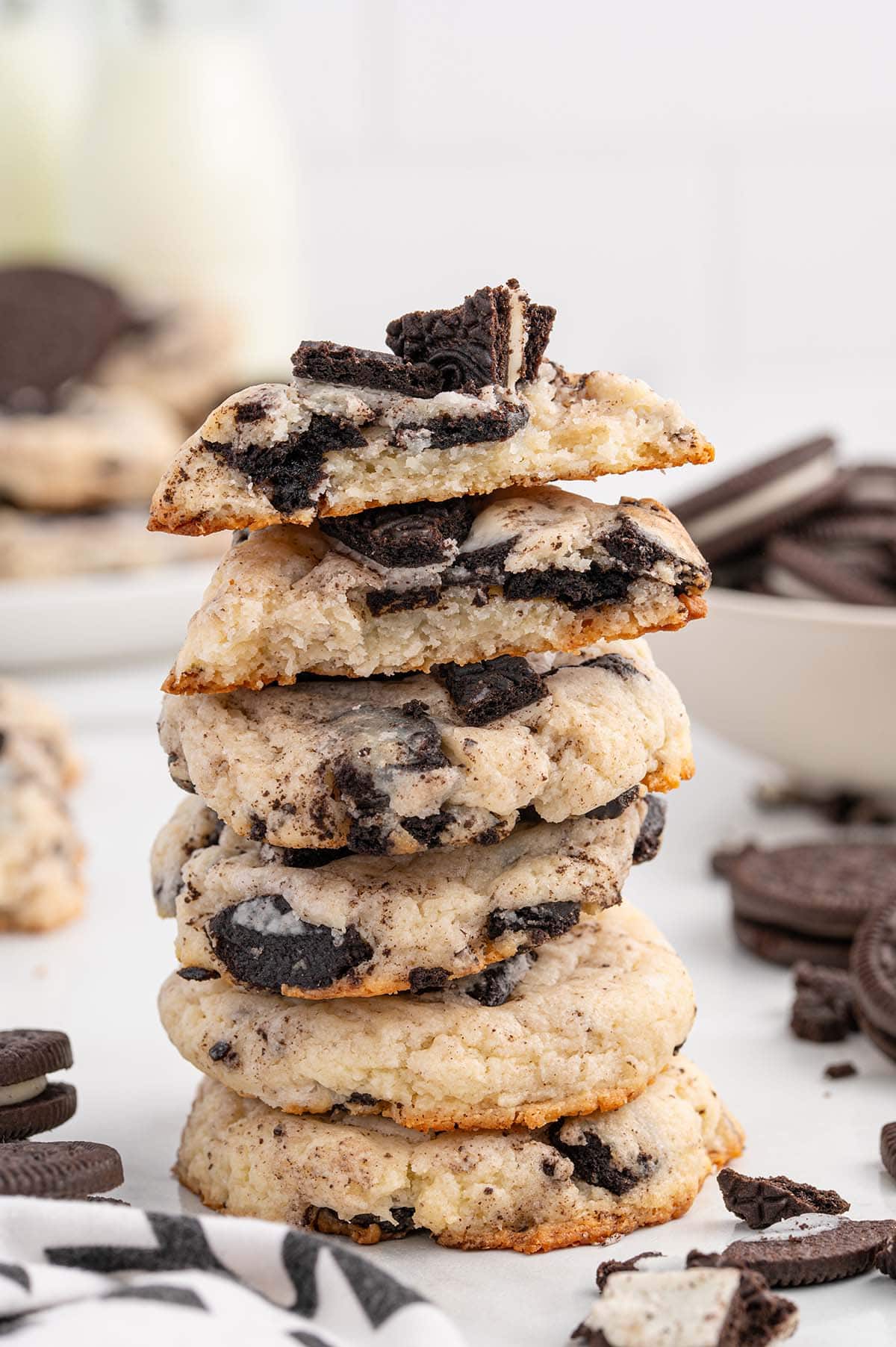 A stack of Oreo cheesecake cookies with a bitten cookie on top, surrounded by Oreo pieces.