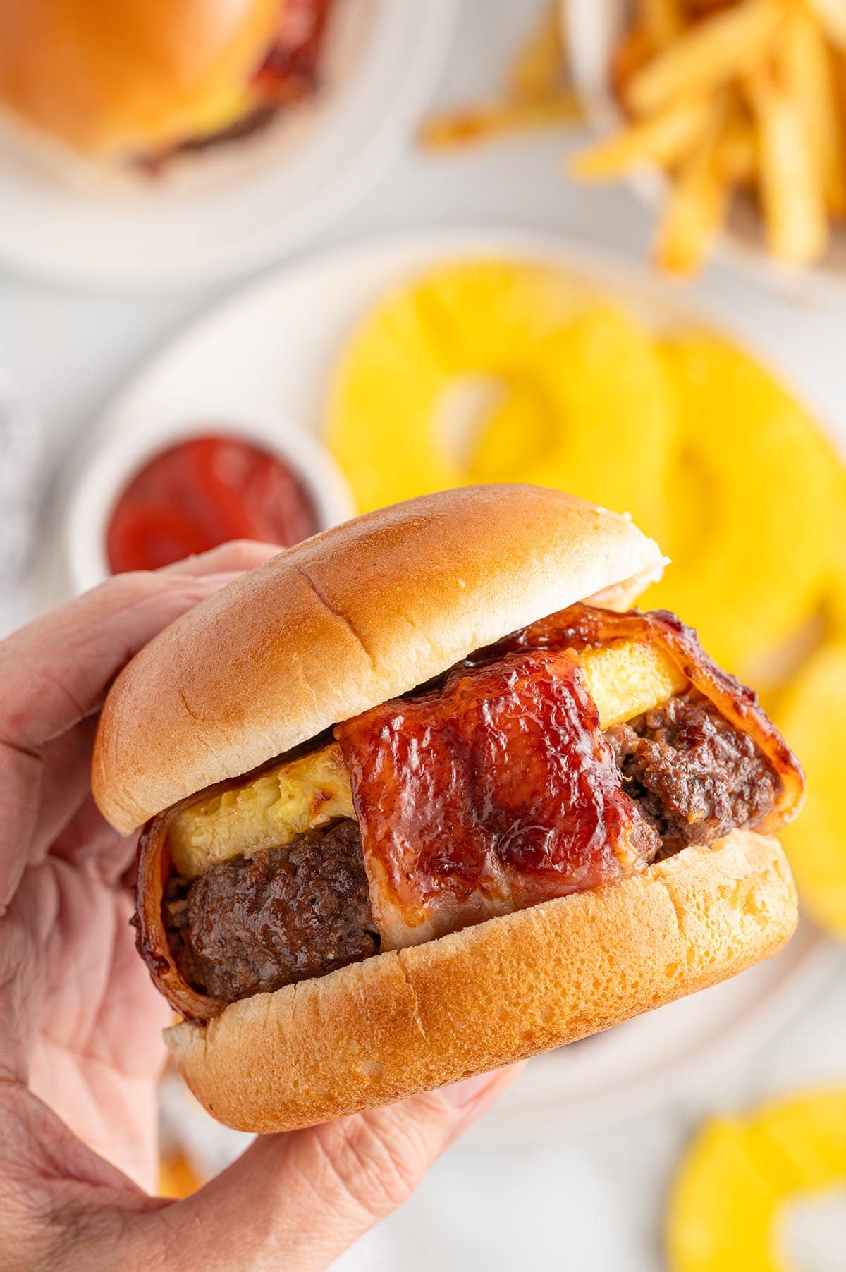 hand holding pineapple bacon burger. 