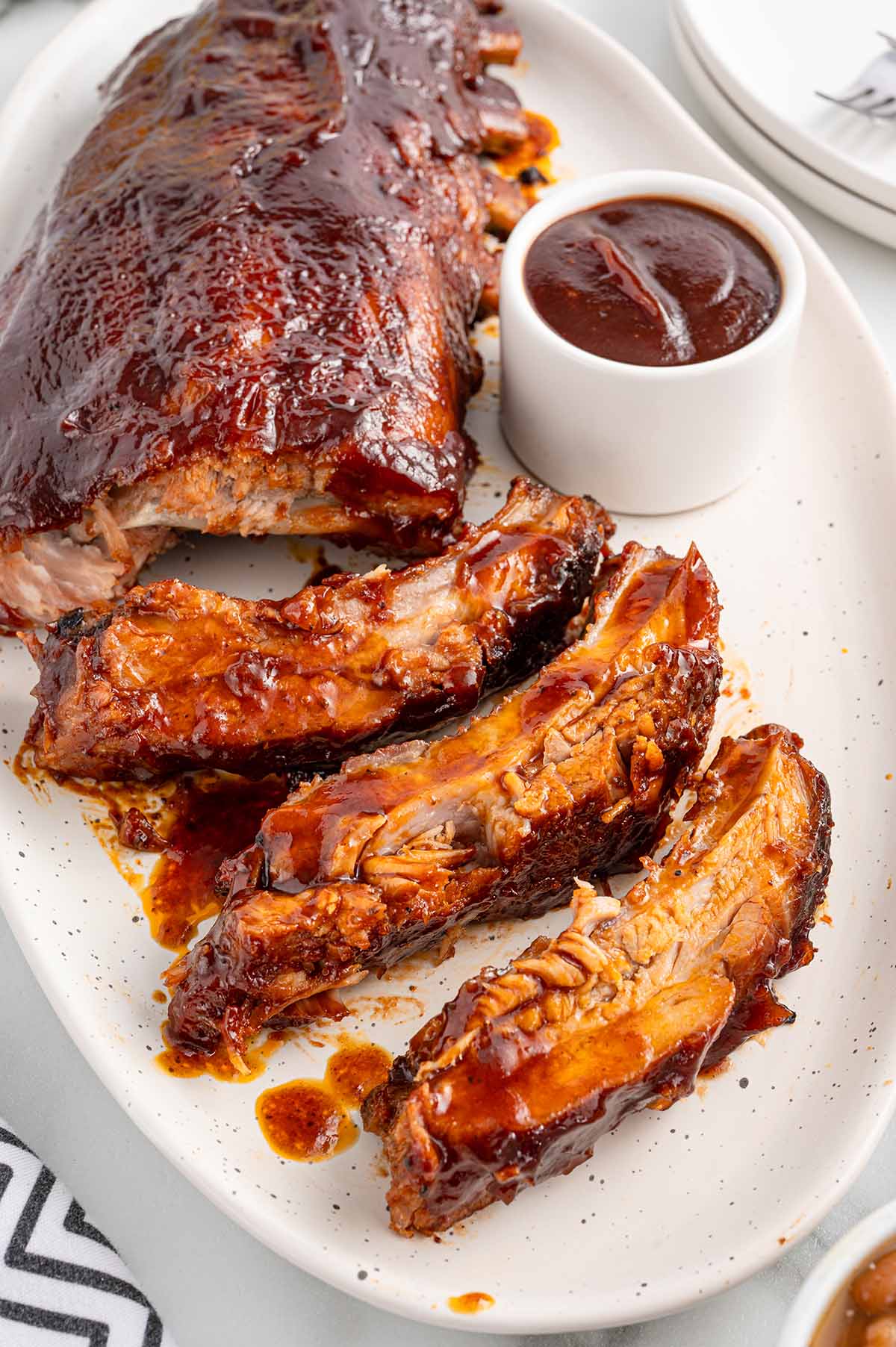 Slow Cooker Baby Back Ribs sliced on a plate with barbecue sauce.