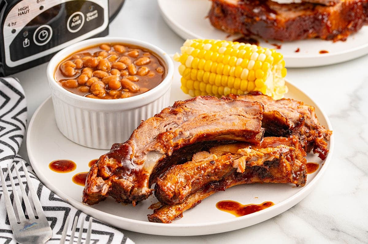 Slow Cooker Baby Back Ribs served with baked beans and corn on the cob.