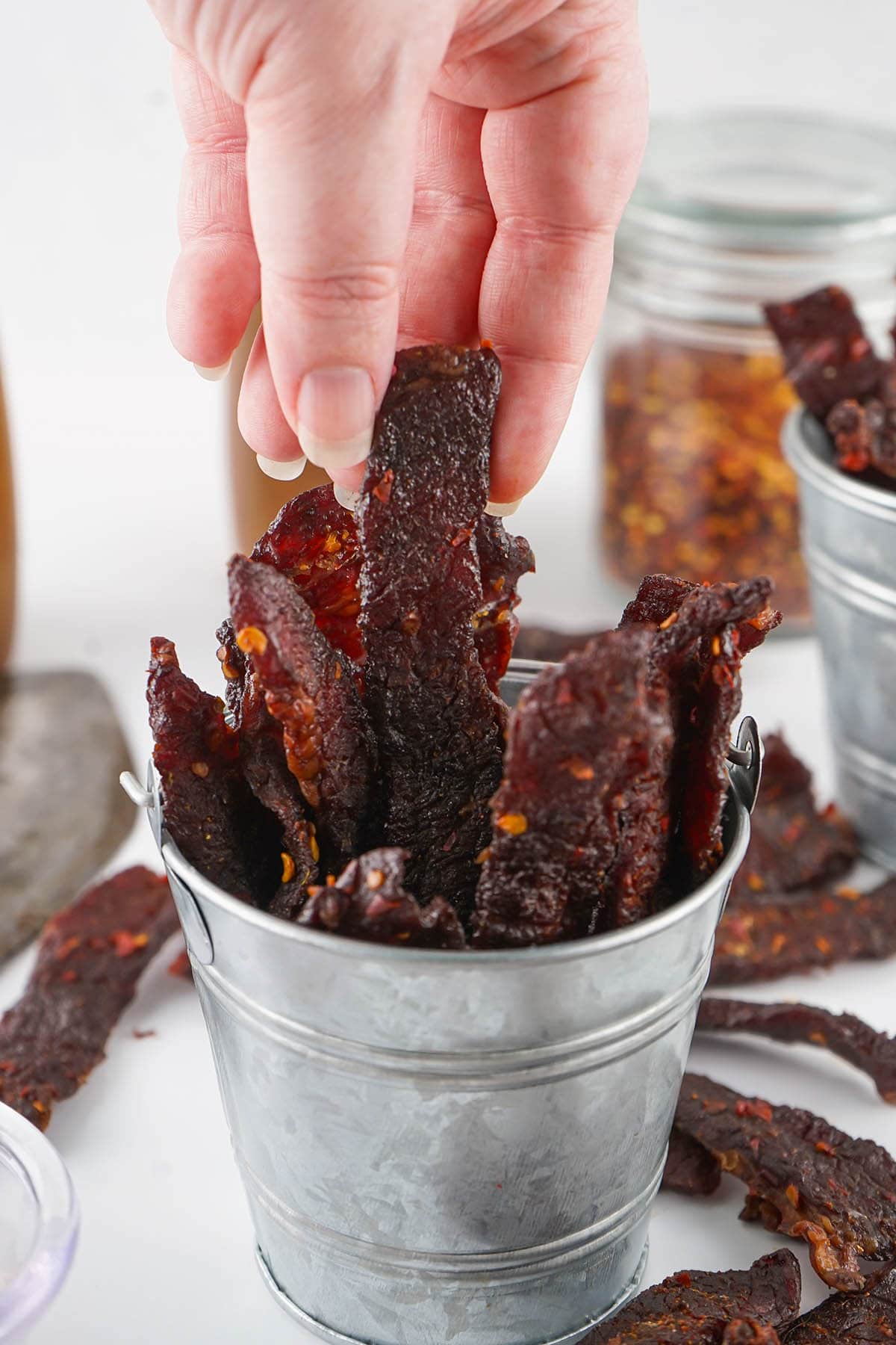 hand picking out Smoked Beef Jerky from a metal basket. 