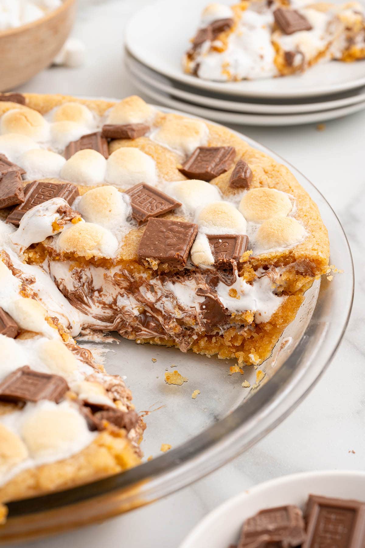 Partially sliced s'mores pie with melted chocolate and toasted marshmallows.