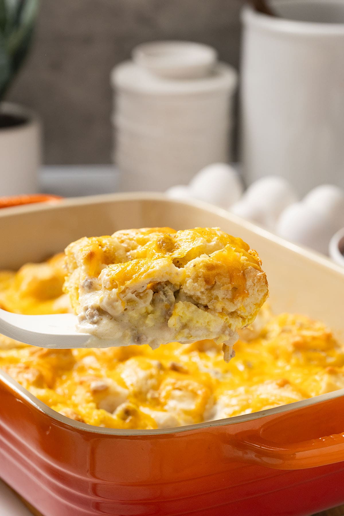 Spoonful of biscuits and gravy casserole with sausage and melted cheese.