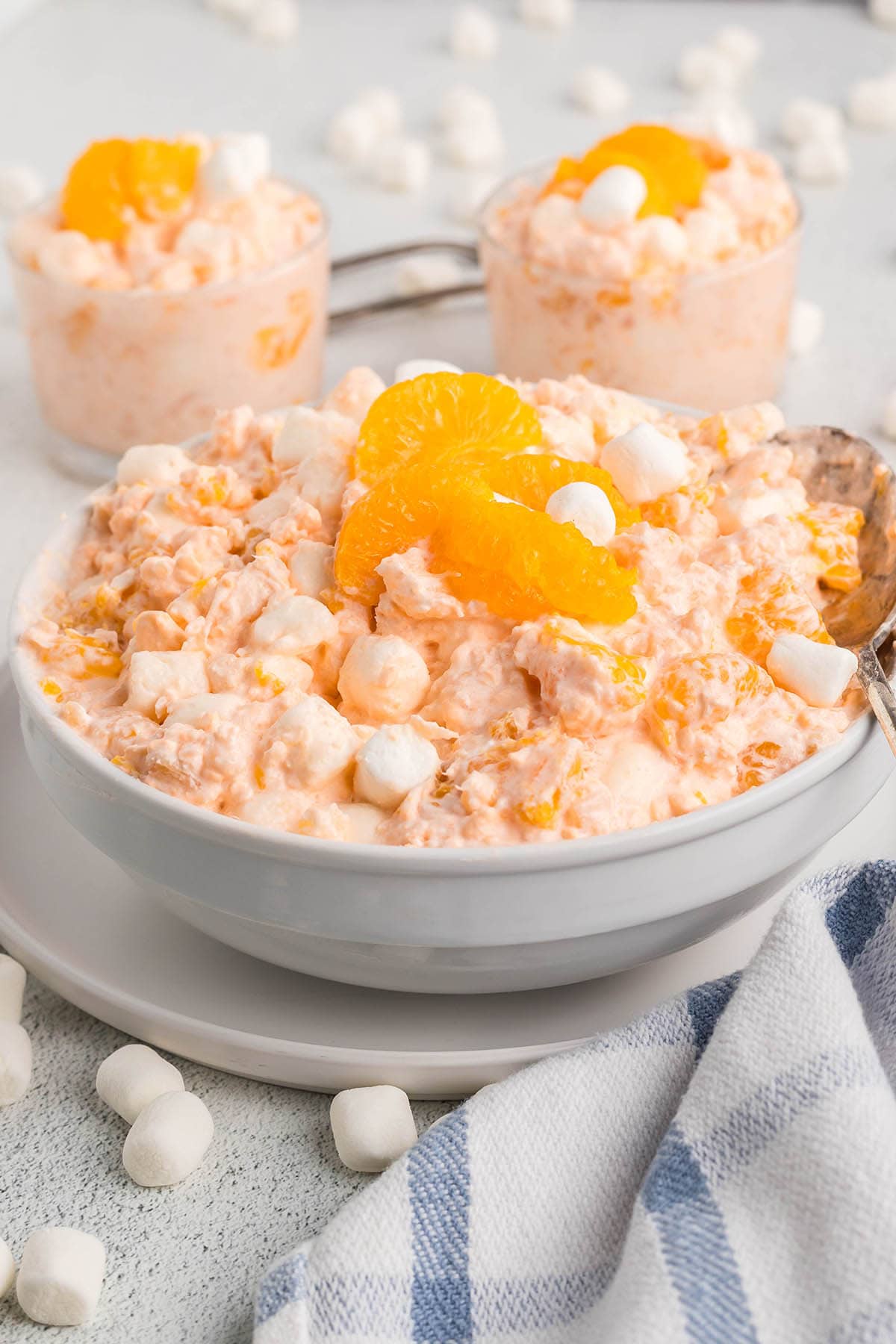 Cottage cheese Jello salad with mandarin oranges and mini marshmallows in a white bowl.