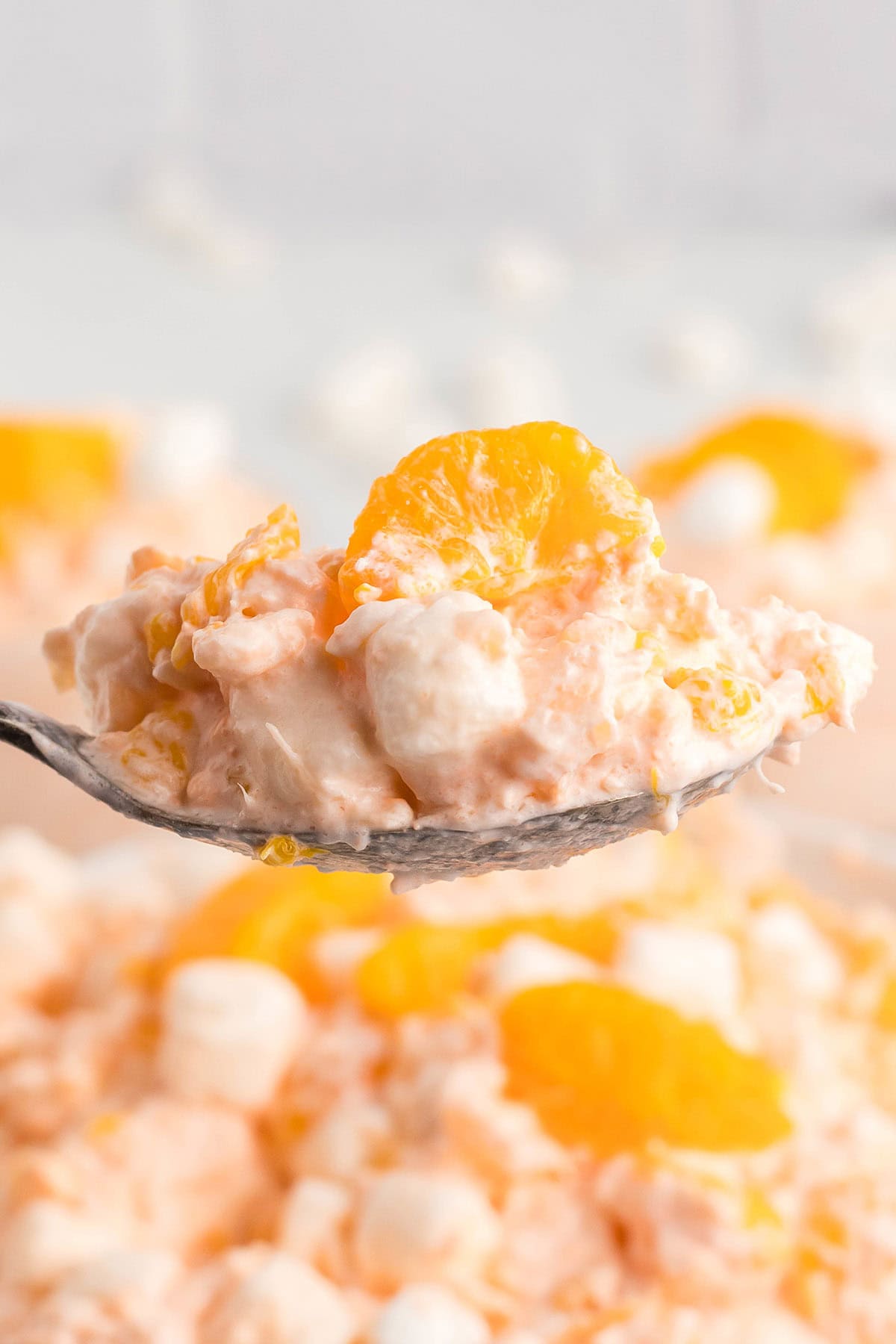 Spoonful of cottage cheese Jello salad with mandarin oranges and mini marshmallows.