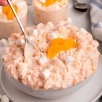 Cottage cheese Jello salad with mandarin oranges and mini marshmallows in a bowl.