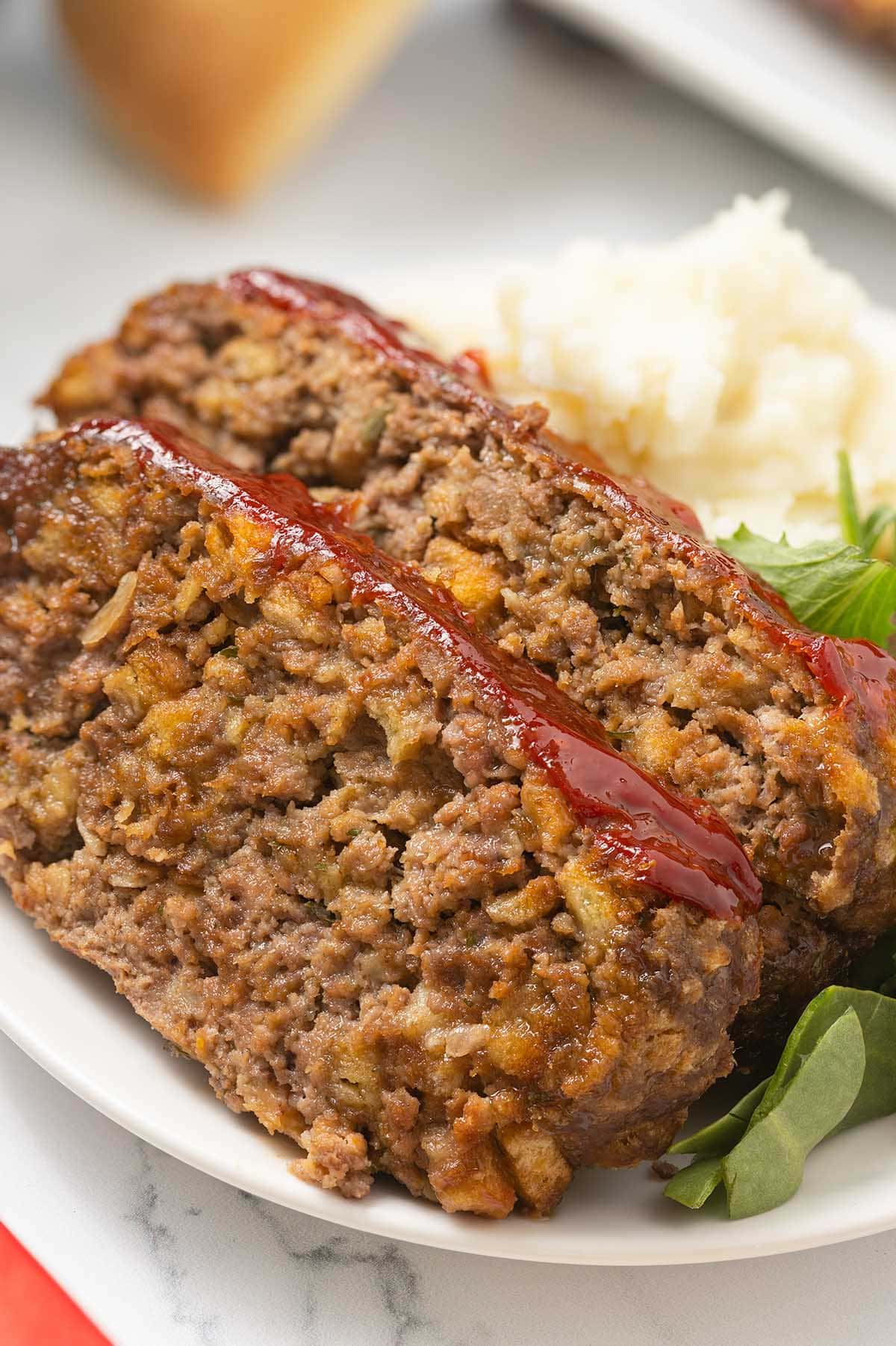 Two slices of Stove Top Stuffing Meatloaf with a ketchup glaze, served with mashed potatoes.