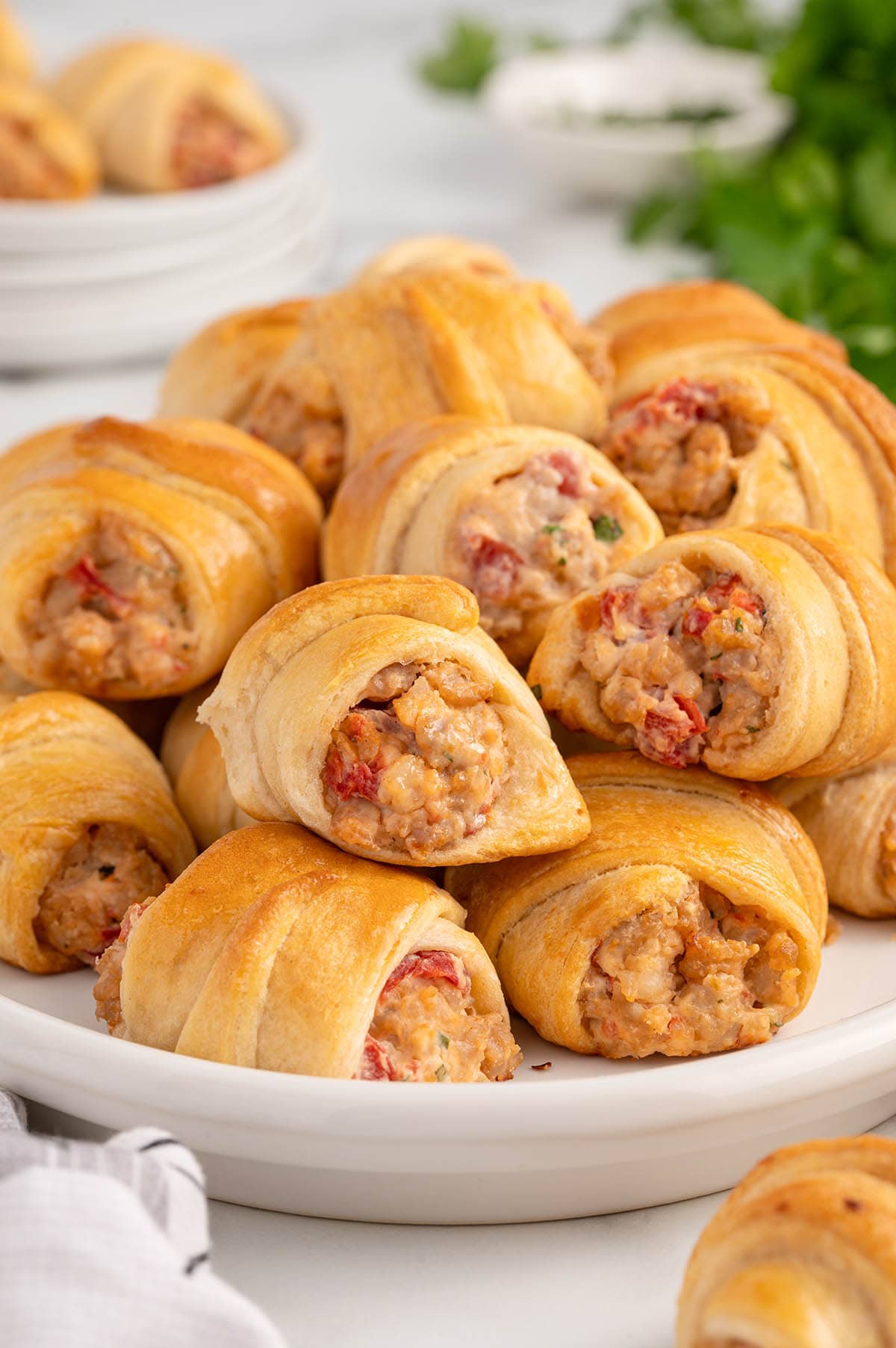 Sausage Cream Cheese Crescent Rolls piled on a white plate.