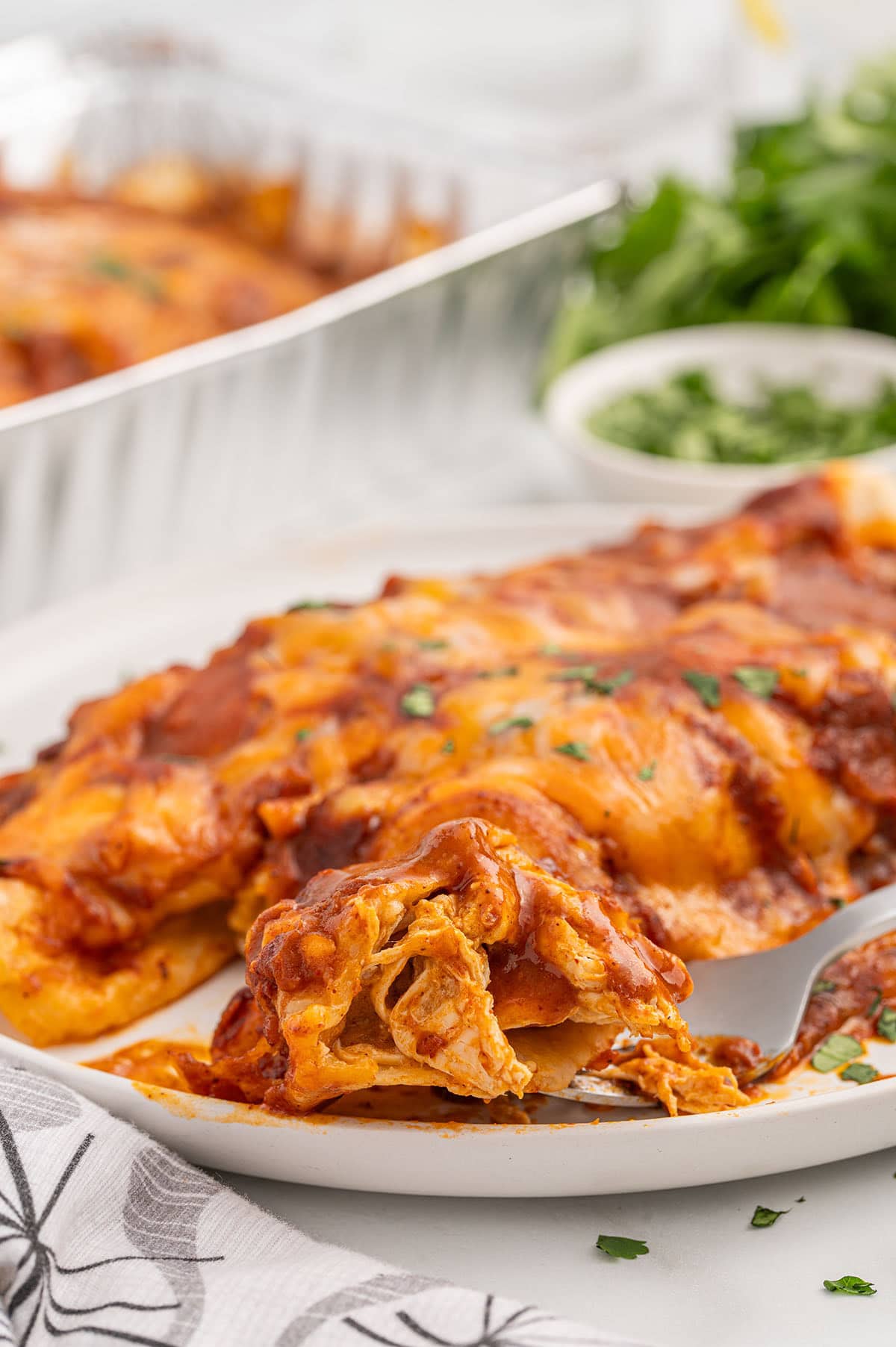 Freezer Enchiladas served on a plate with melted cheese and shredded chicken.