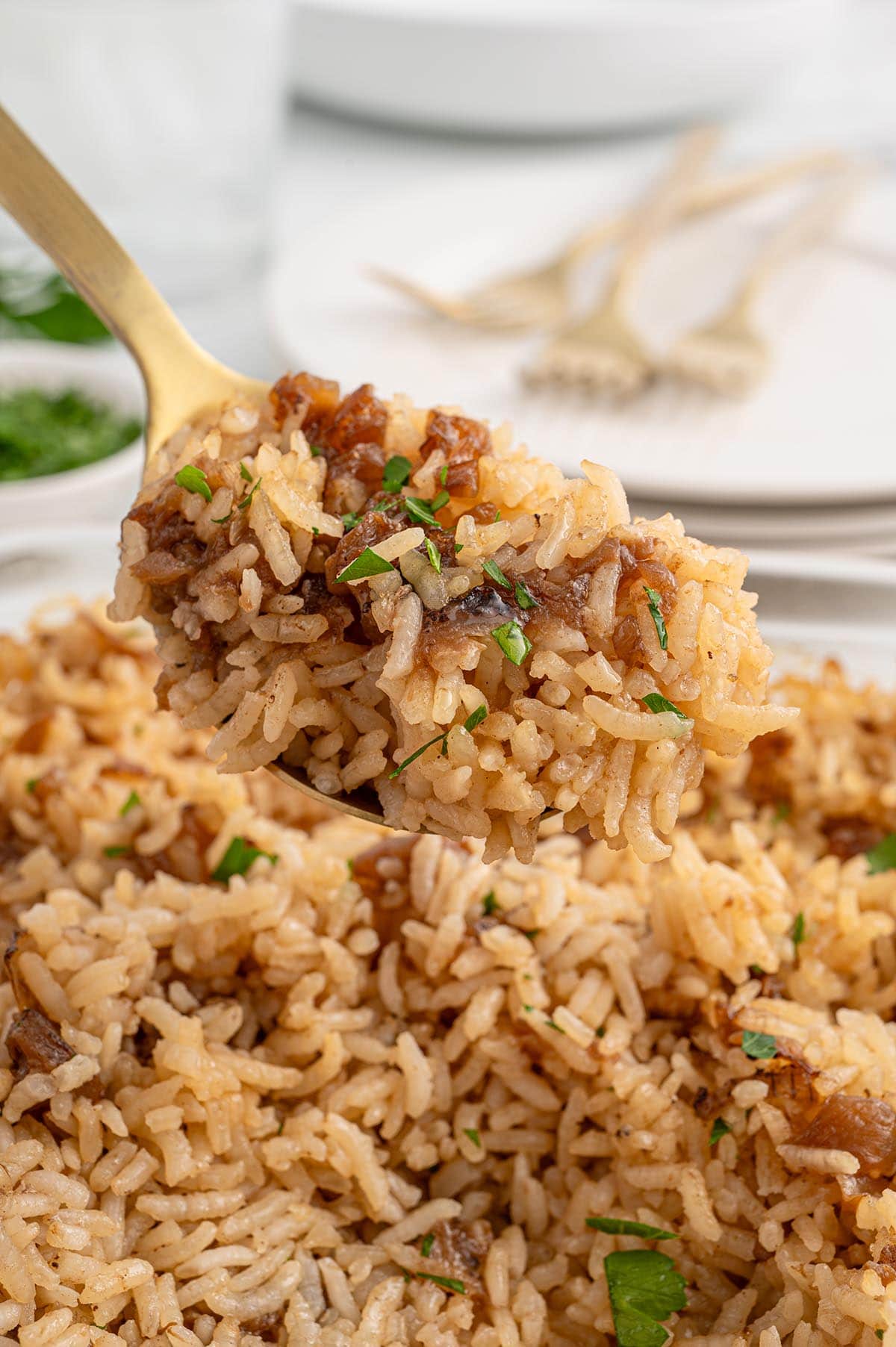 French Onion Rice with caramelized onions and parsley on a gold fork.