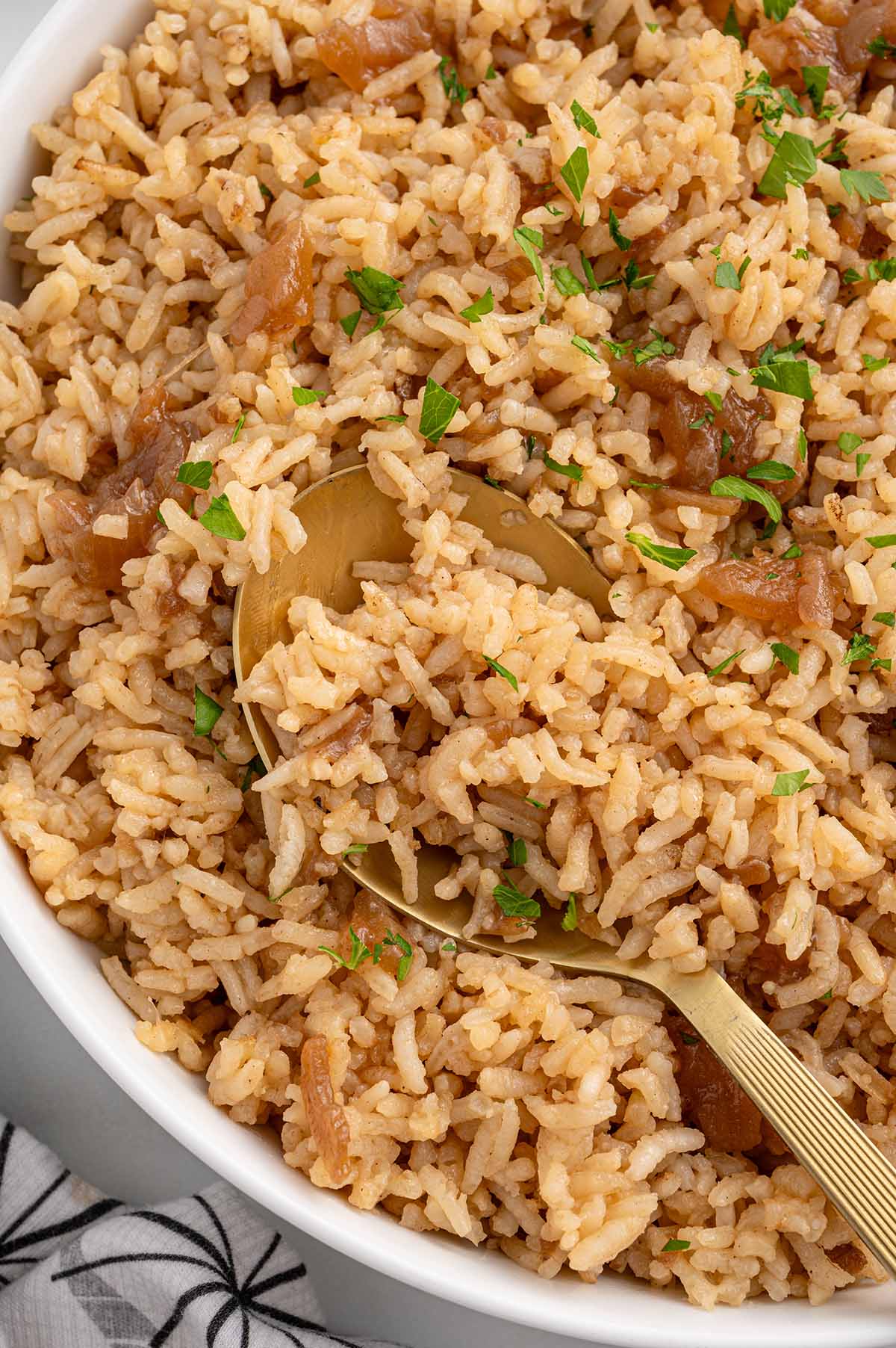 French Onion Rice garnished with parsley and served with a gold spoon.