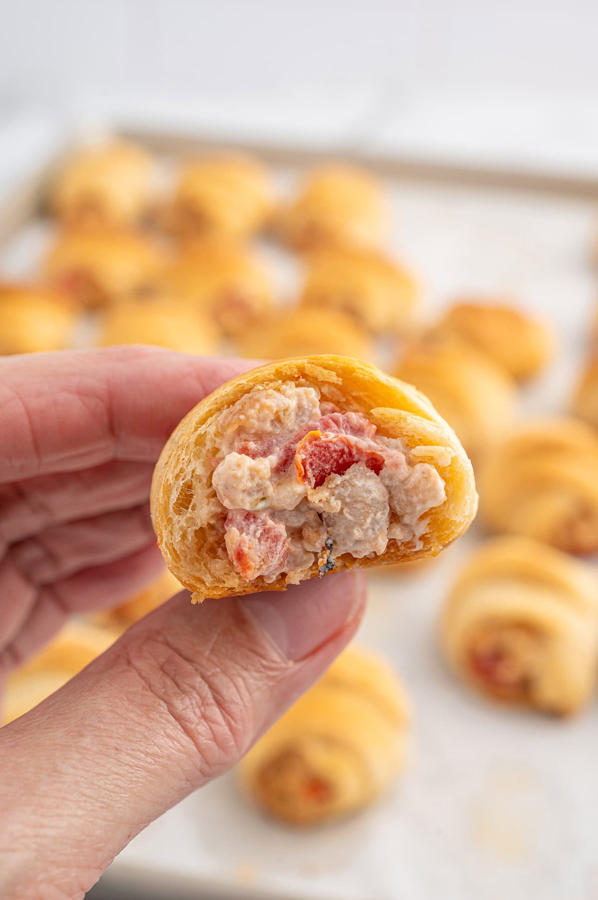 Sausage Cream Cheese Crescent Roll with filling visible, held in hand.