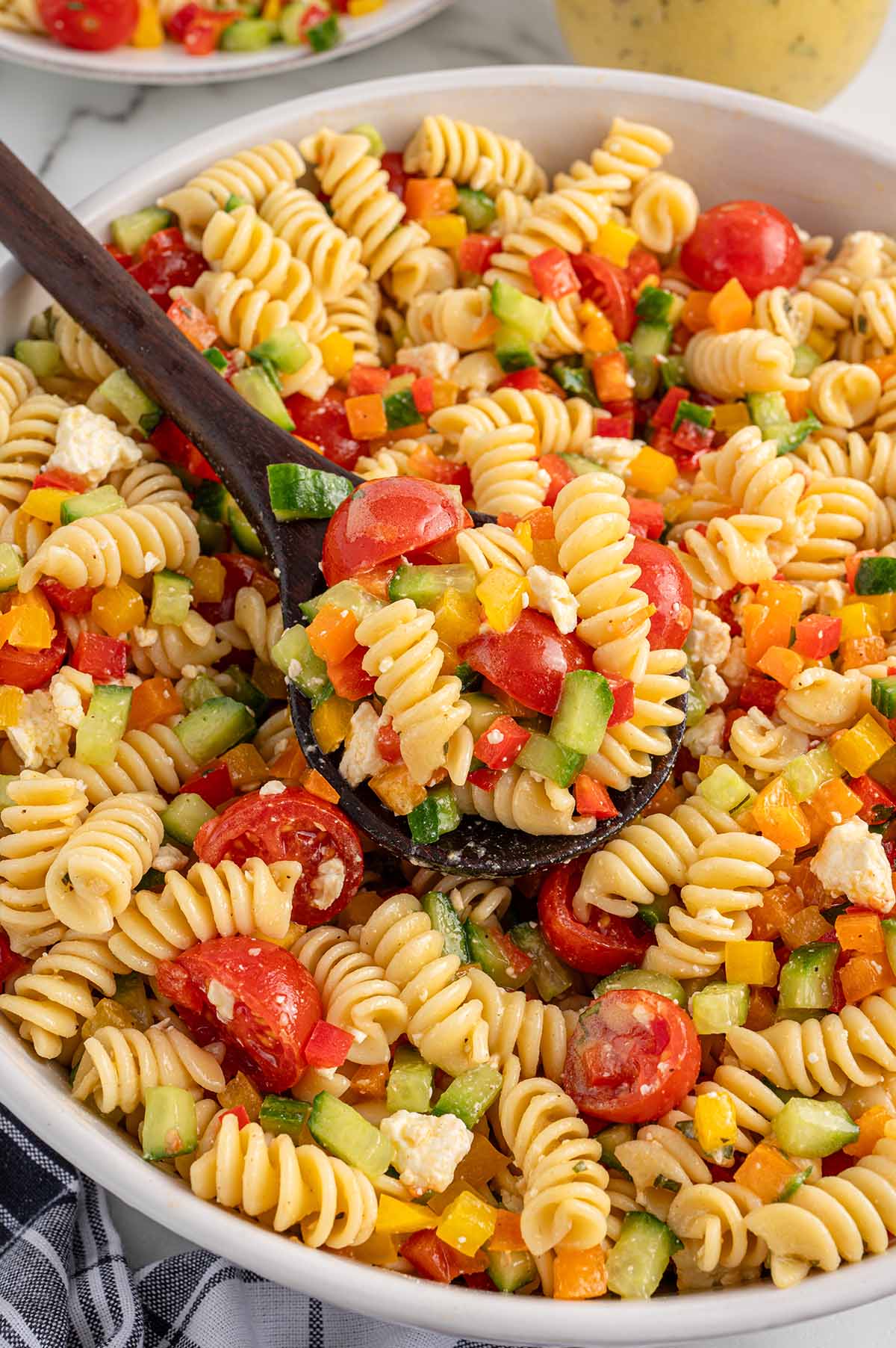 scoop summer pasta salad with wooden spoon.