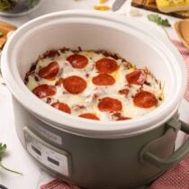 Crock pot pizza topped with melted mozzarella cheese and pepperoni slices, cooked directly in a slow cooker.