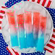 Red, white, and blue homemade bomb pops on ice with American flag napkins.