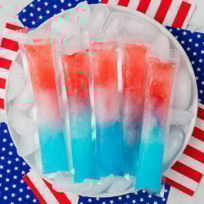 Red, white, and blue homemade bomb pops on ice with American flag napkins.