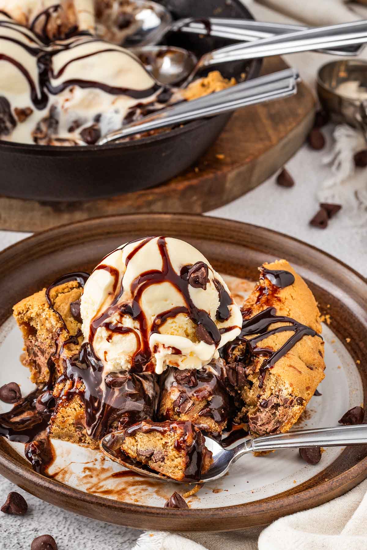 Pizookie dessert with ice cream and chocolate syrup in a skillet.