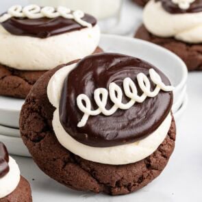 Chocolate Hostess-inspired cookies topped with swirls of white icing and a layer of cream and ganache.
