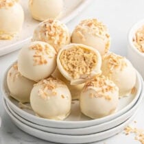 Piña colada truffles topped with toasted coconut, one cut open to reveal the creamy center.