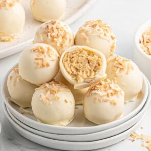 Piña colada truffles topped with toasted coconut, one cut open to reveal the creamy center.