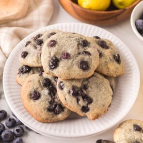Plate of soft lemon blueberry cookies with fresh blueberries.