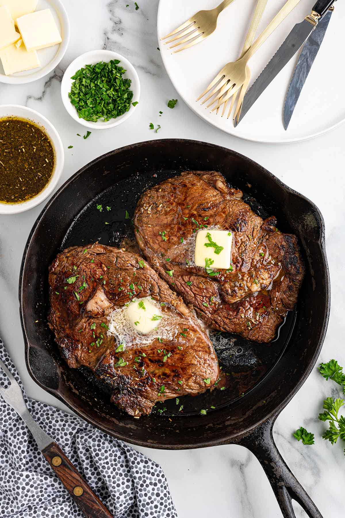 a top view of two steak marinade in a skillet with butter on top