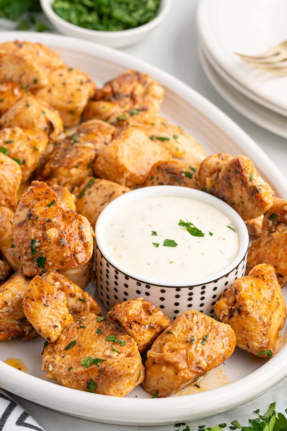 garlic butter chicken bites served on a white plate with dipping sauce