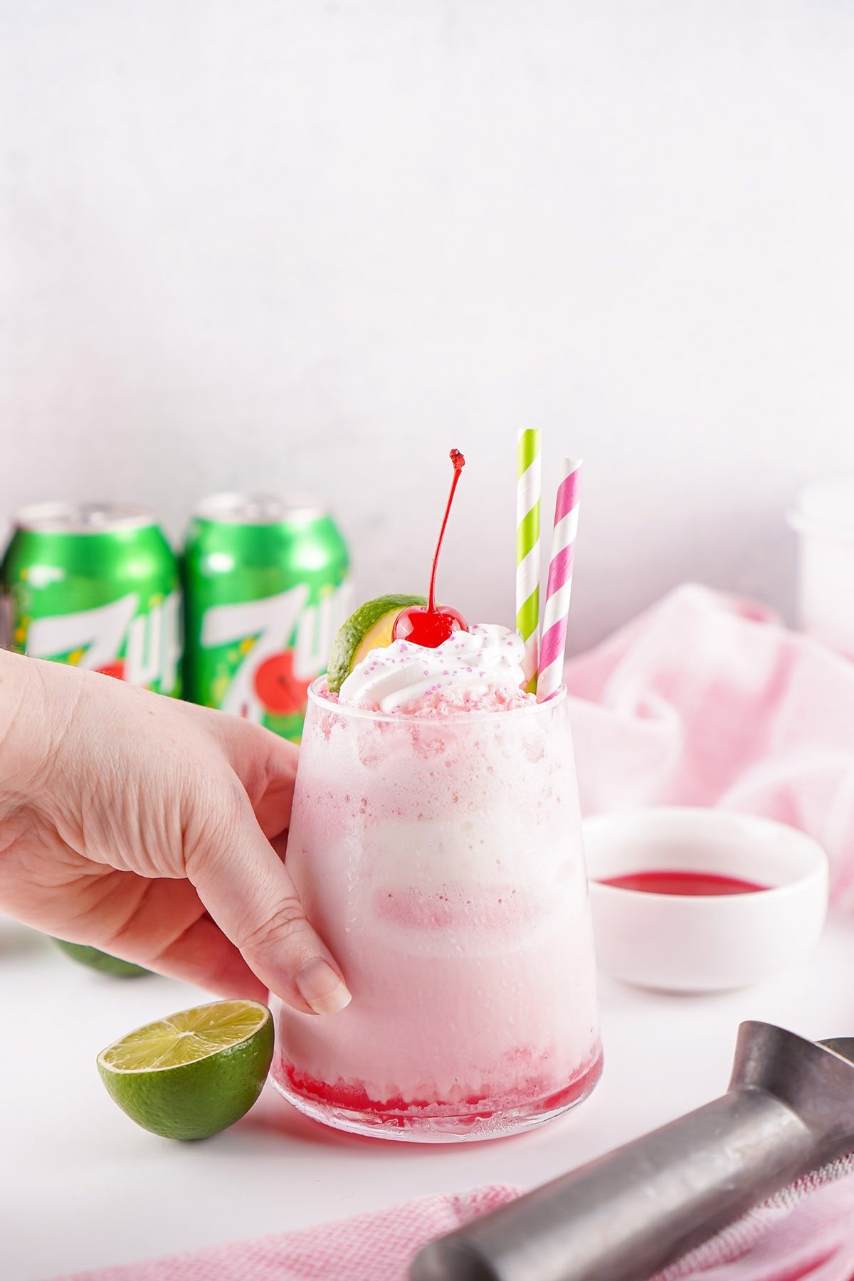 Shirley temple drink surrounded by lime, 7UP cans.