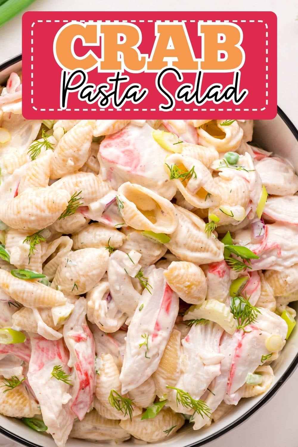 Creamy crab pasta salad topped with imitation crab and veggies served inside a bowl.