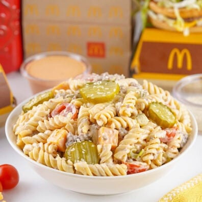 White bowl filled with creamy rotini pasta salad and pickles.