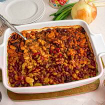 calico beans in casserole dish with a spoon.