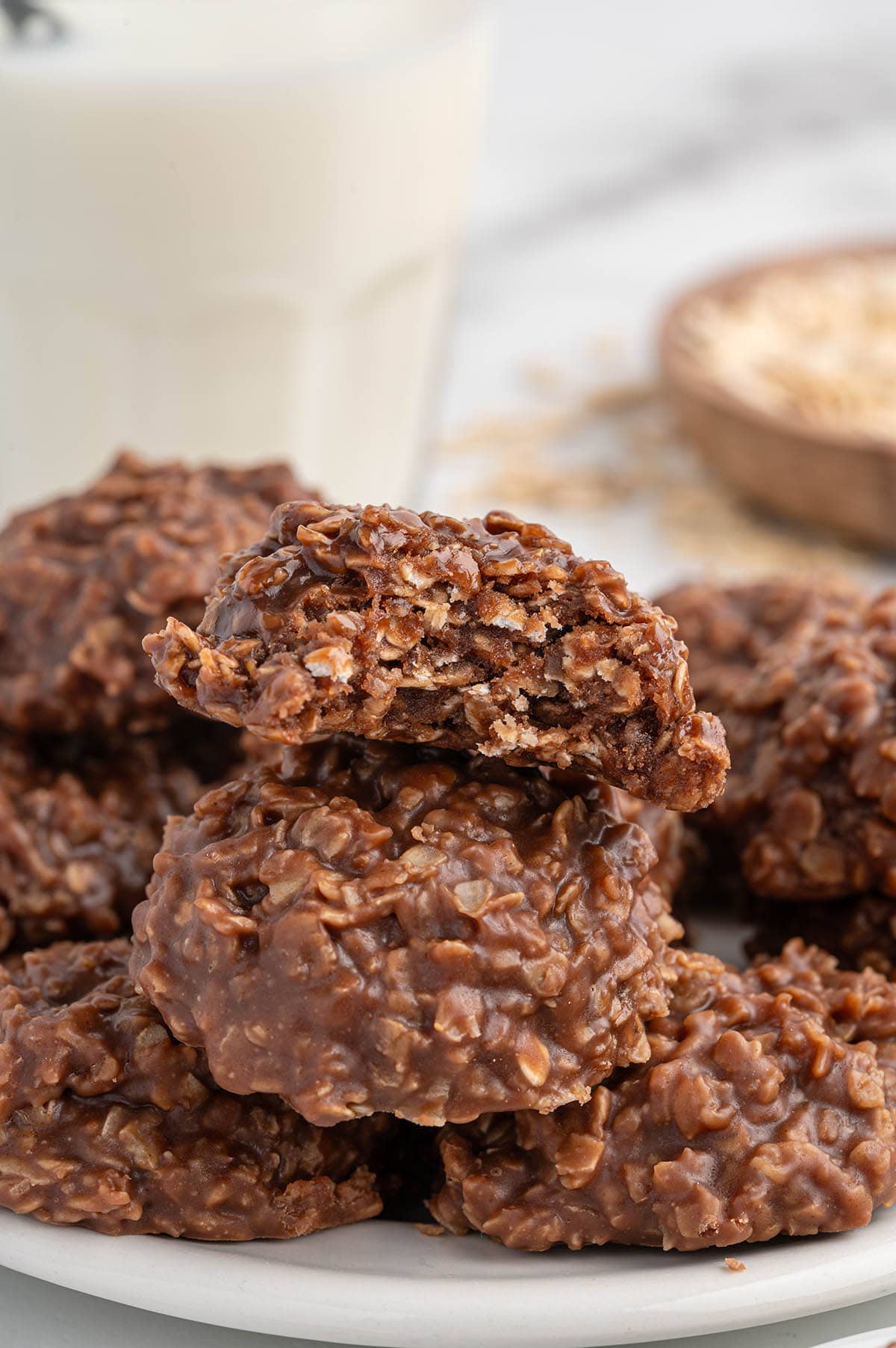 A close-up of chocolate peanut butter no bake cookies stacked on a white plate.