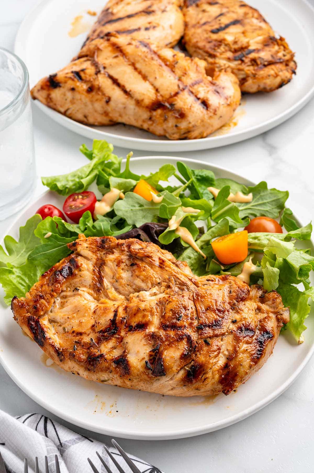 Grilled chicken breast served with fresh mixed greens and cherry tomatoes.