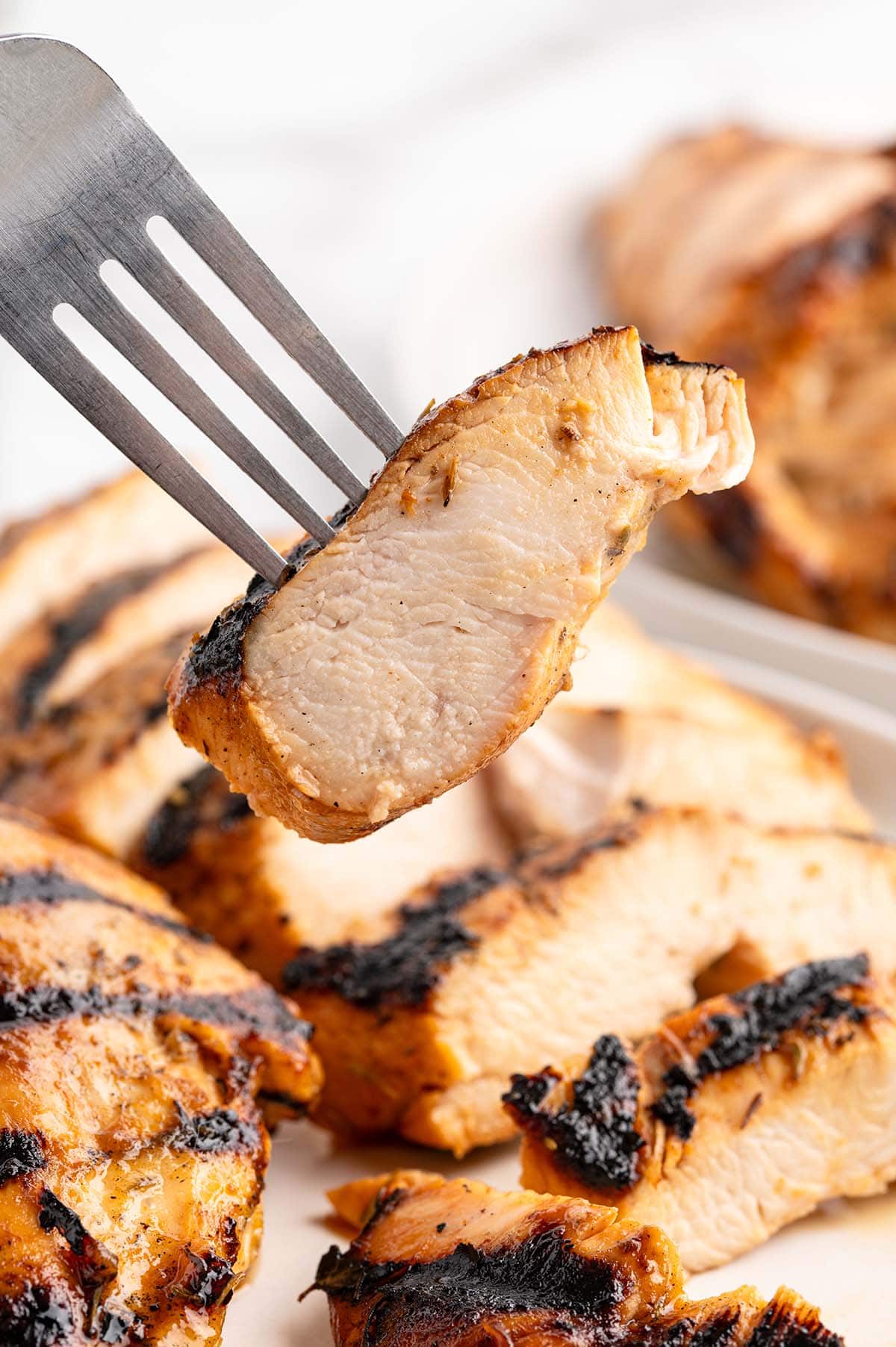 Juicy grilled chicken breast with visible char marks on a fork.