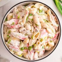 Close-up of a creamy crab pasta salad with shell pasta and fresh herbs.