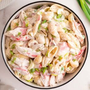 Close-up of a creamy crab pasta salad with shell pasta and fresh herbs.