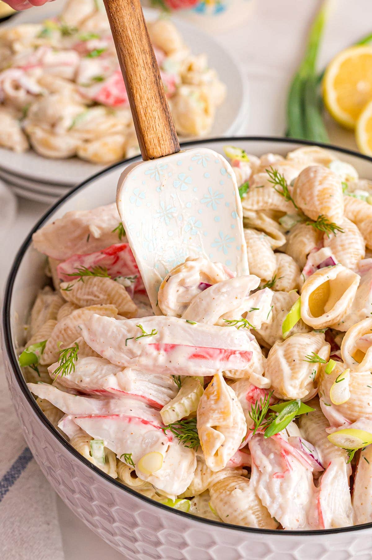 Shell pasta mixed with crab meat and fresh herbs in a white bowl.