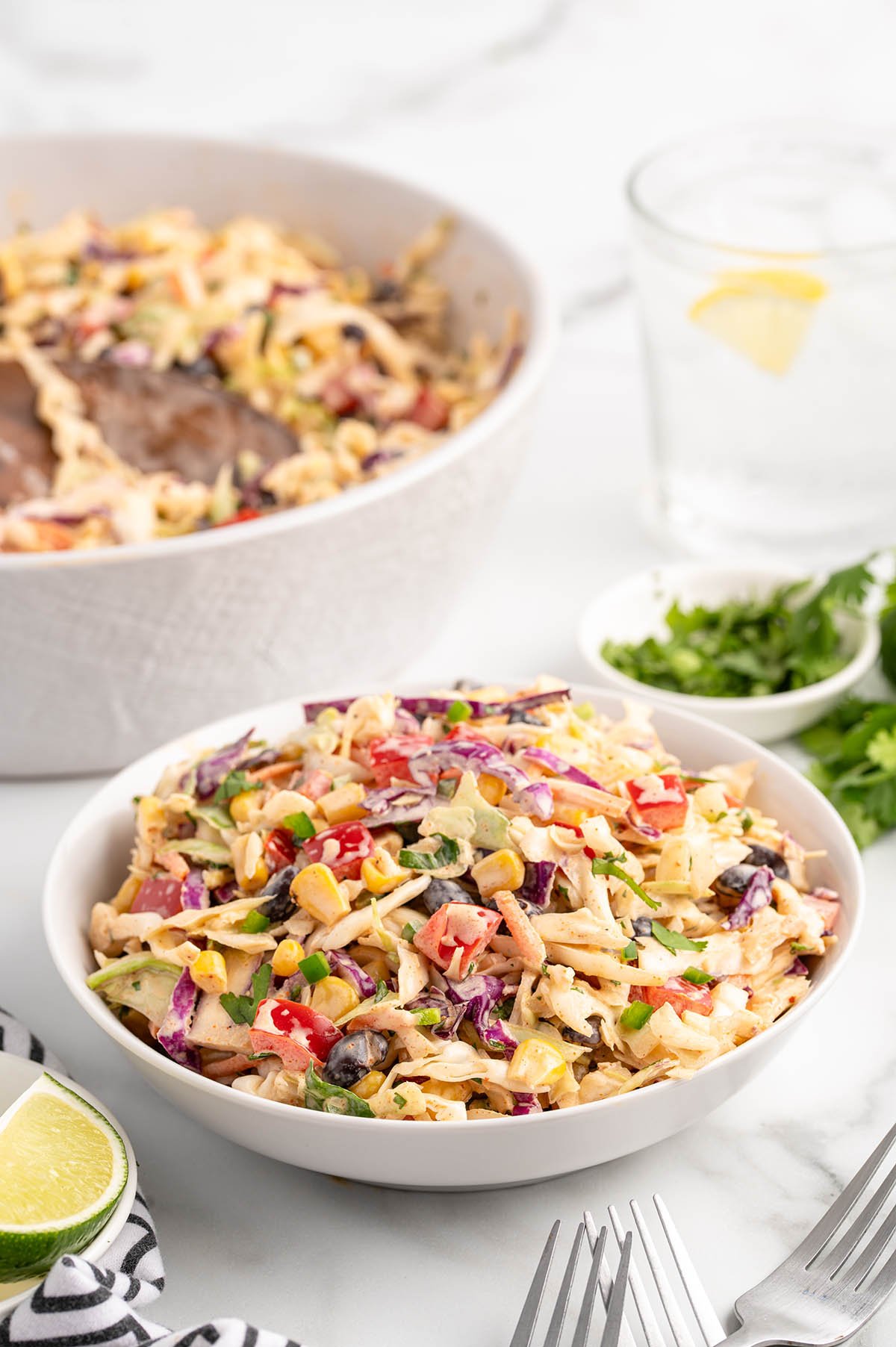 A bowl of colorful Mexican coleslaw with corn, red cabbage, and fresh herbs.