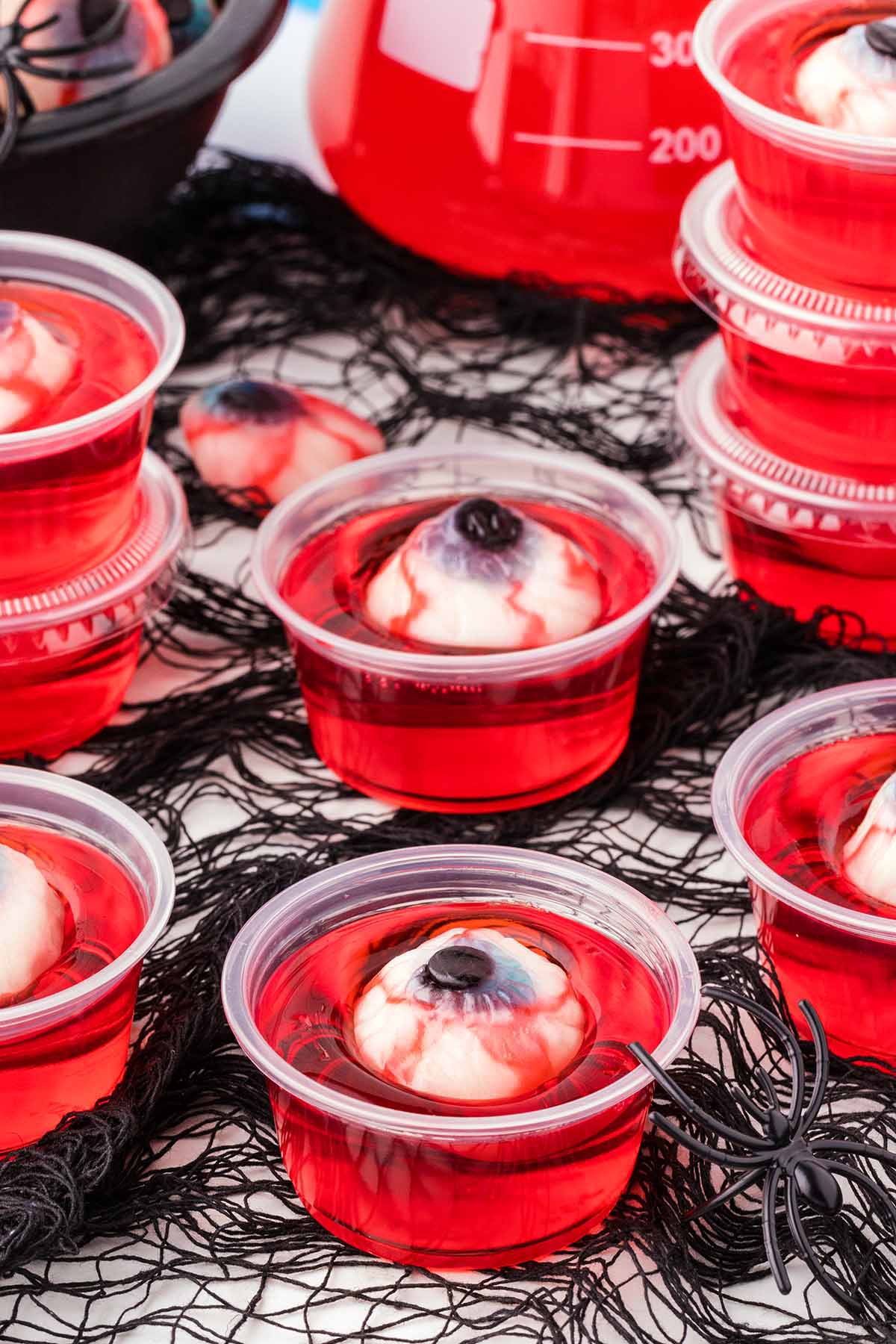 Jello shots with a spooky eyeball design set on a black net background.