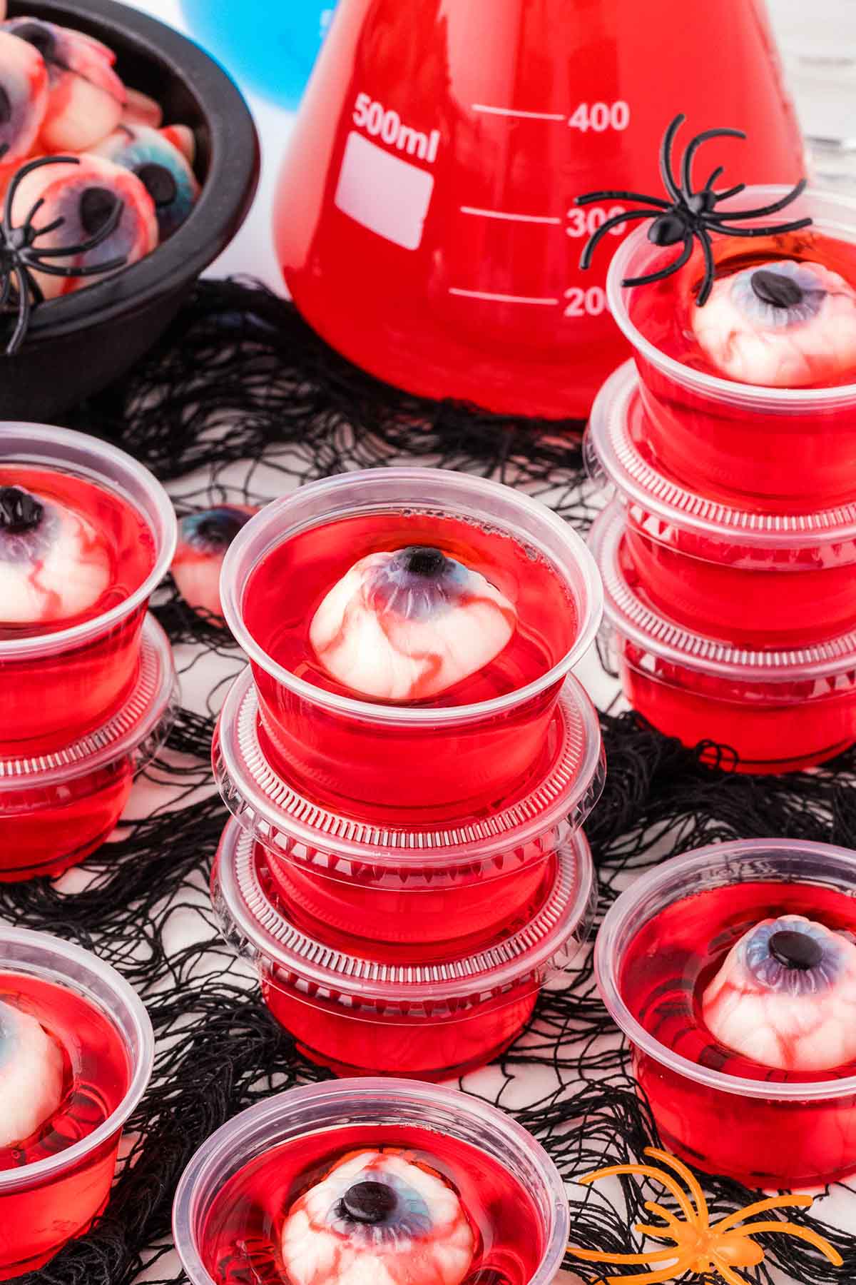 Red jello shots featuring creepy eyeball gummies in each cup.