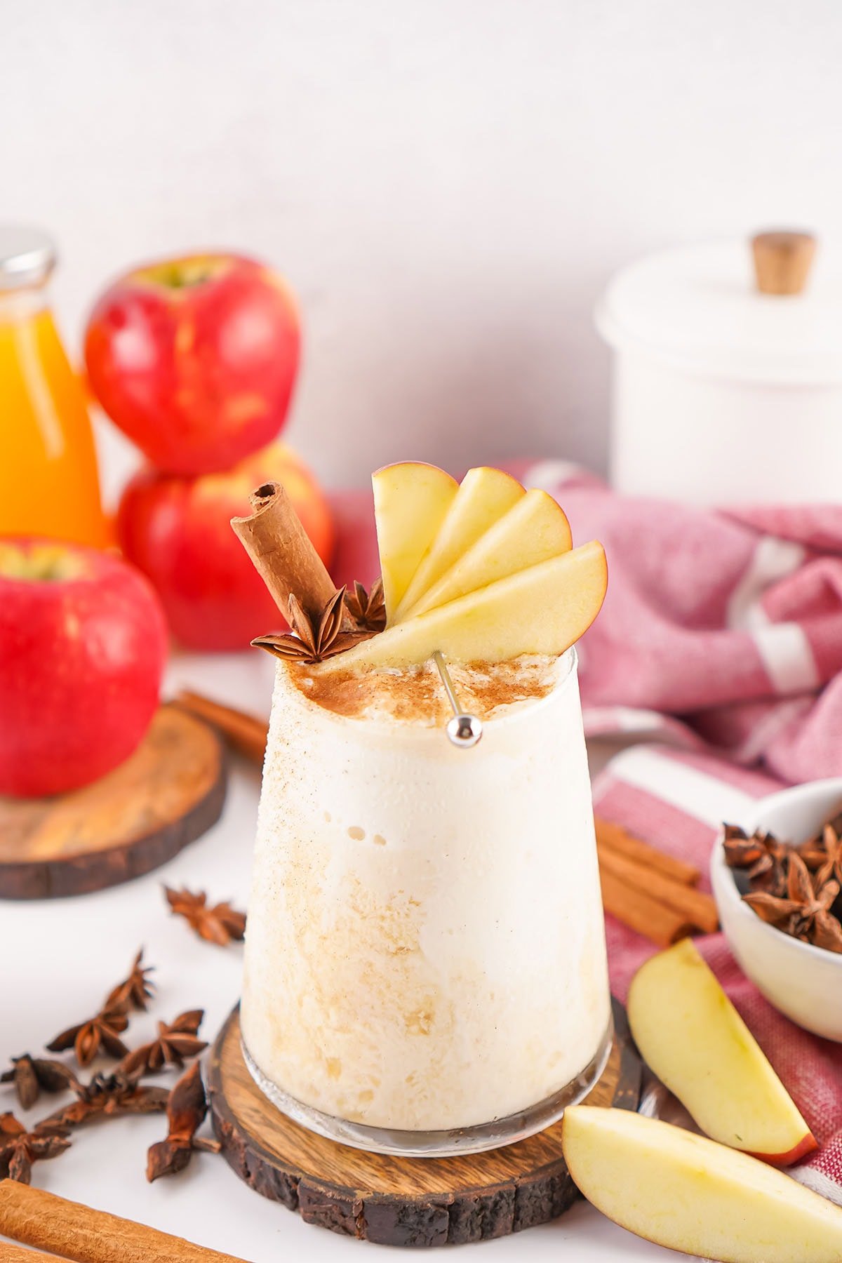 A creamy apple cider float topped with fresh apple slices and cinnamon sticks.