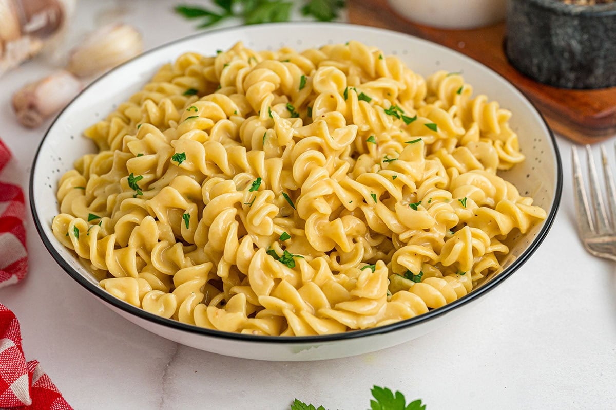 A bowl of creamy rotini pasta with fresh parsley sprinkled on top.