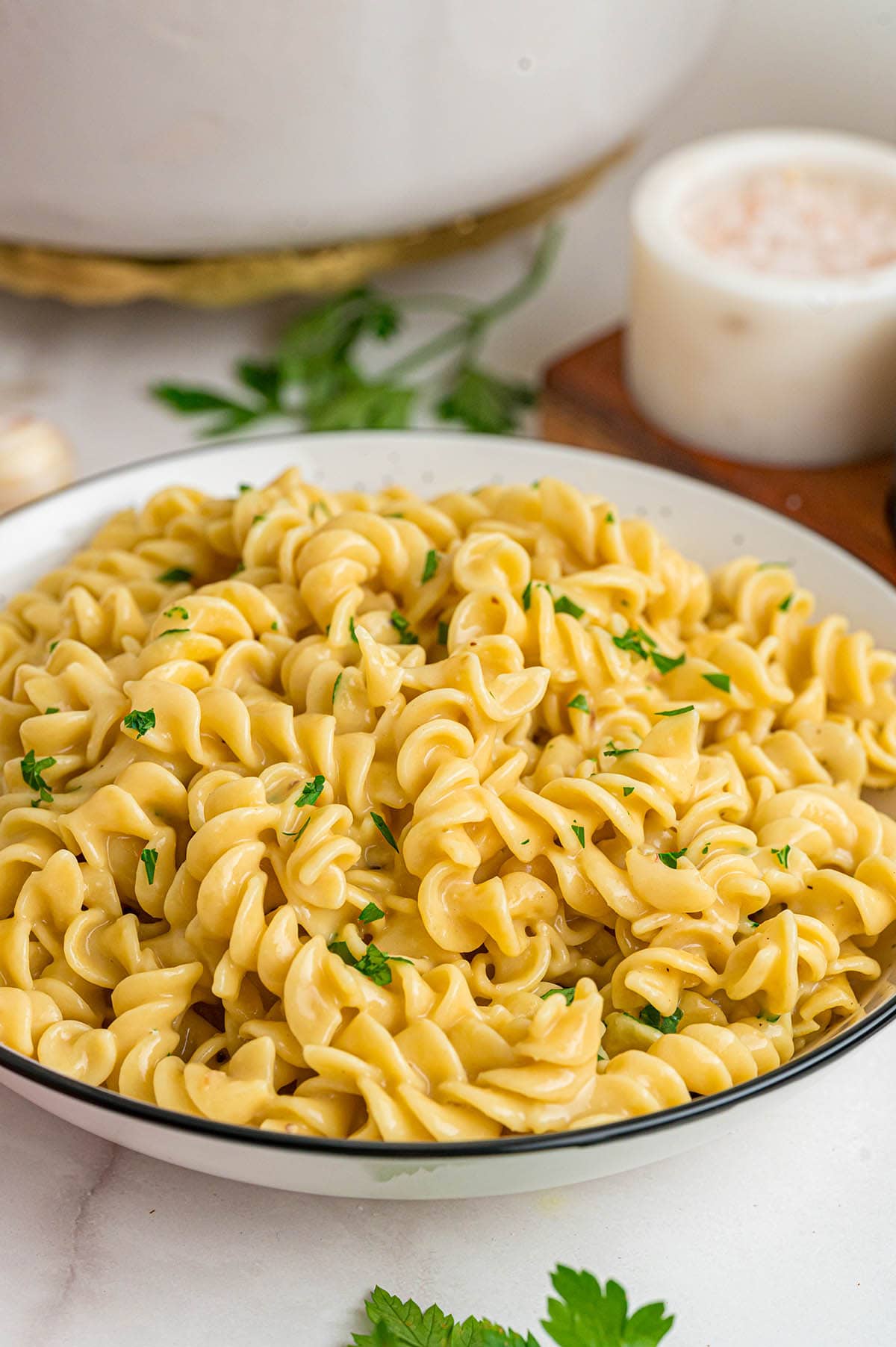 Plate filled with yellow spiral noodles and a sprinkle of green parsley.