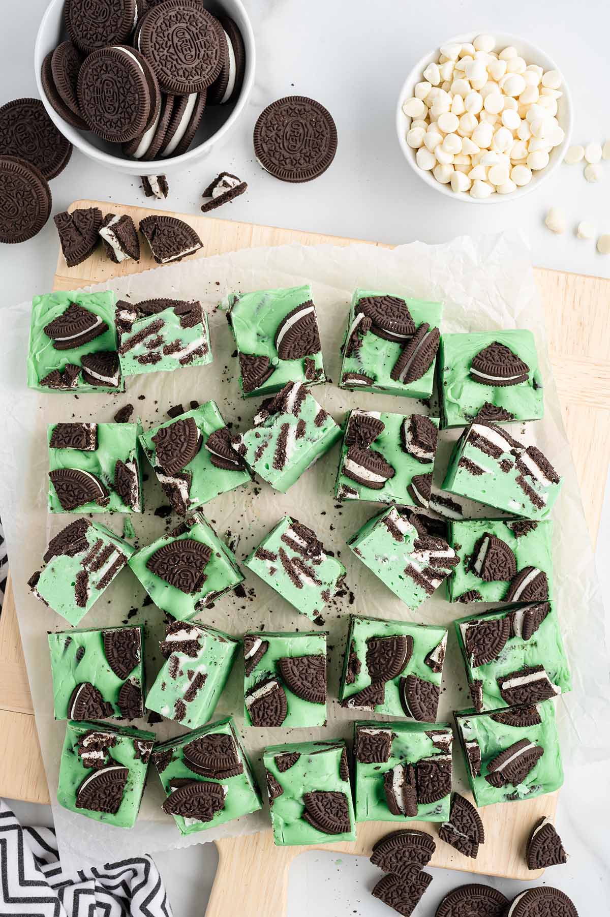 Green minty fudge chunks mixed with chocolate sandwich cookies on a cutting board.