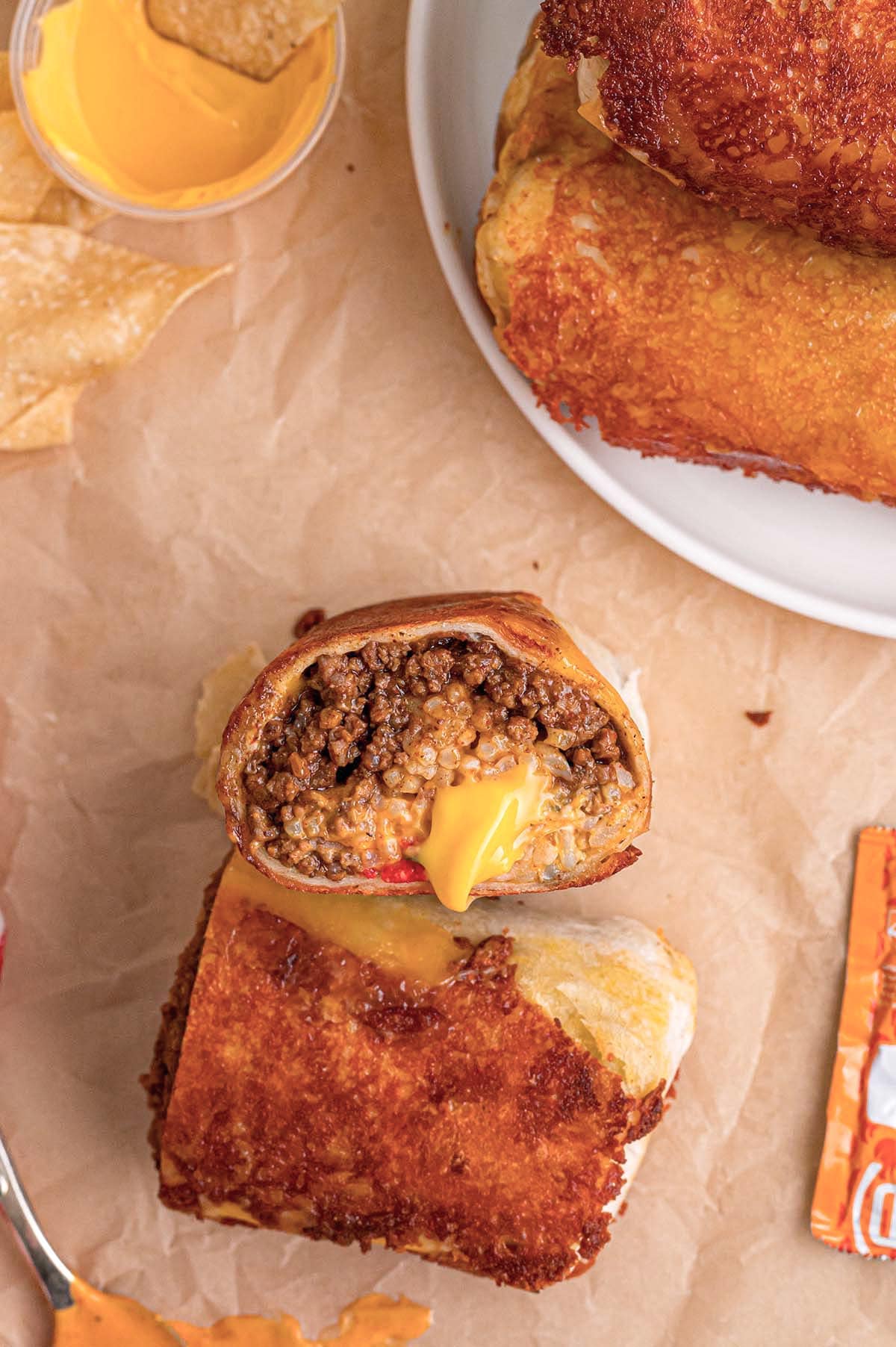 A crispy, golden grilled cheese burrito filled with beef and melted cheese on paper.