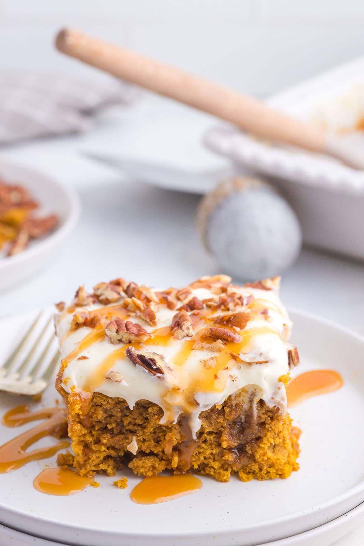 Plate holding a slice of pumpkin poke cake with nuts and sweet syrup.