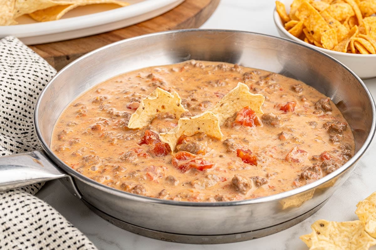 A skillet filled with creamy Rotel dip mixed with ground beef and tomatoes.