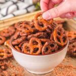 A hand grabbing a cinnamon sugar-coated pretzel from a bowl full of treats.