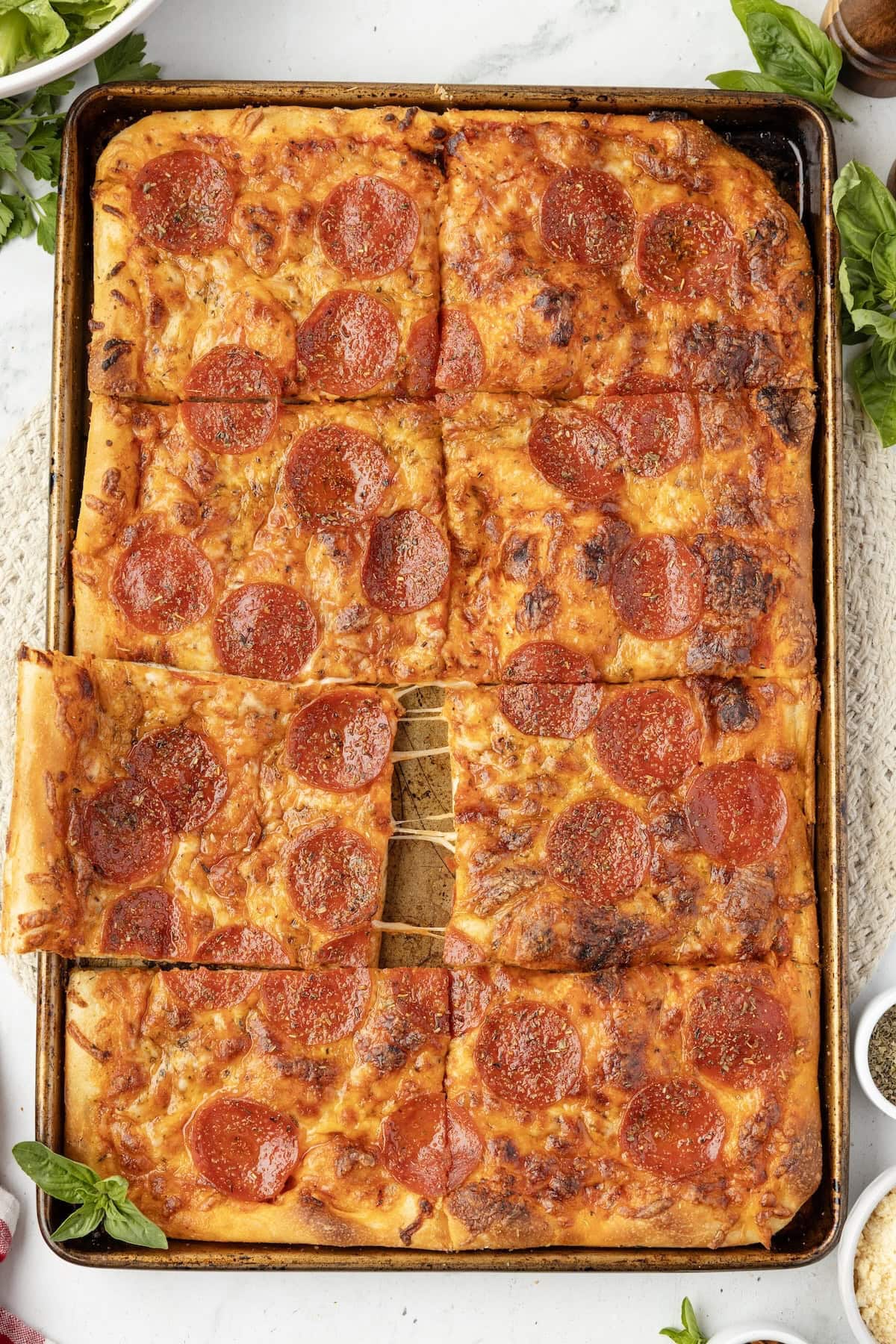 sheet pan pizza placed on to of white table.