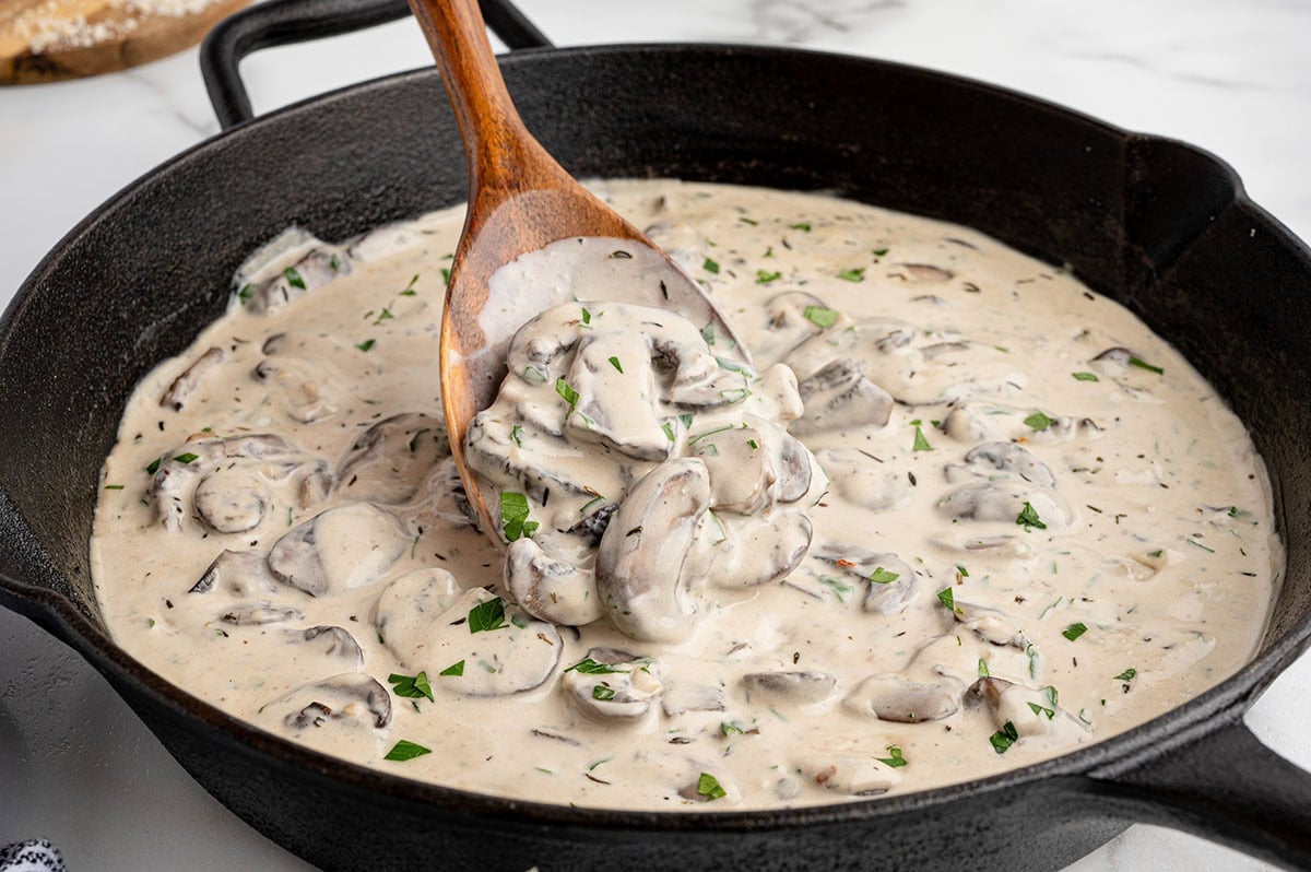 Creamy garlic parmesan mushroom sauce  in a black skillet with fresh herbs.